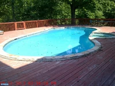 Old freeform pool with weathered red wood deck before renovation
