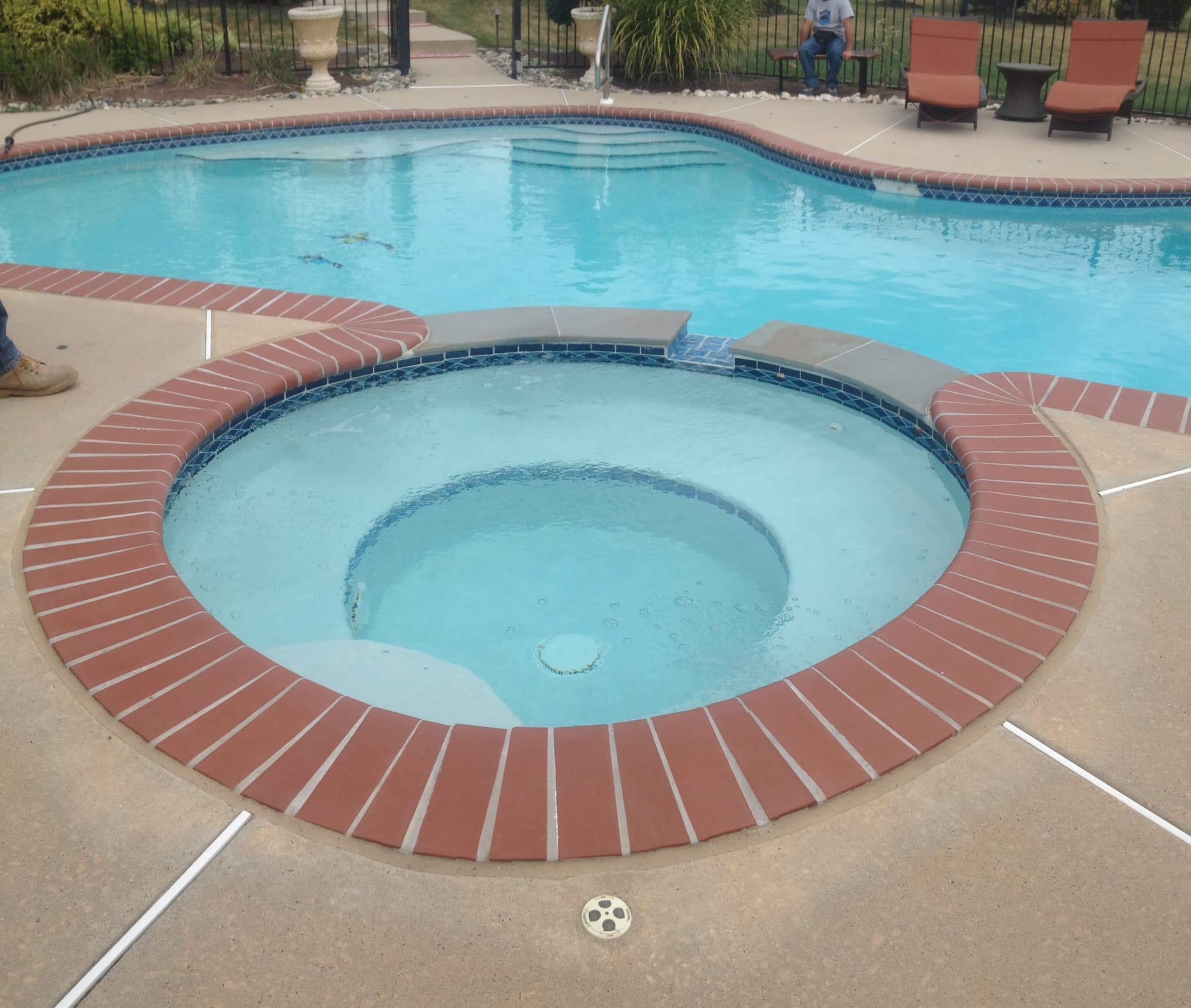 Round spa plastered and drained awaiting water beside completed rectangular pool