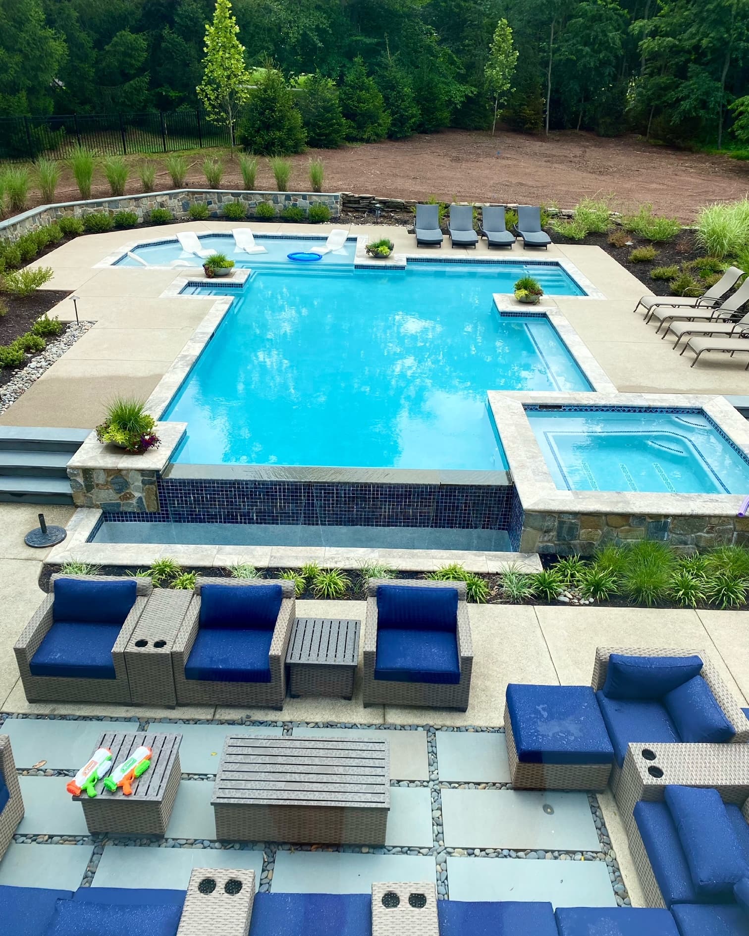 Modern rectangular pool with raised spa and blue sectional outdoor seating area