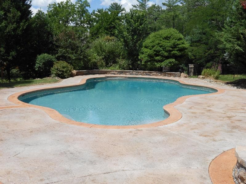Freeform pool drained during renovation with crew demolishing surrounding deck