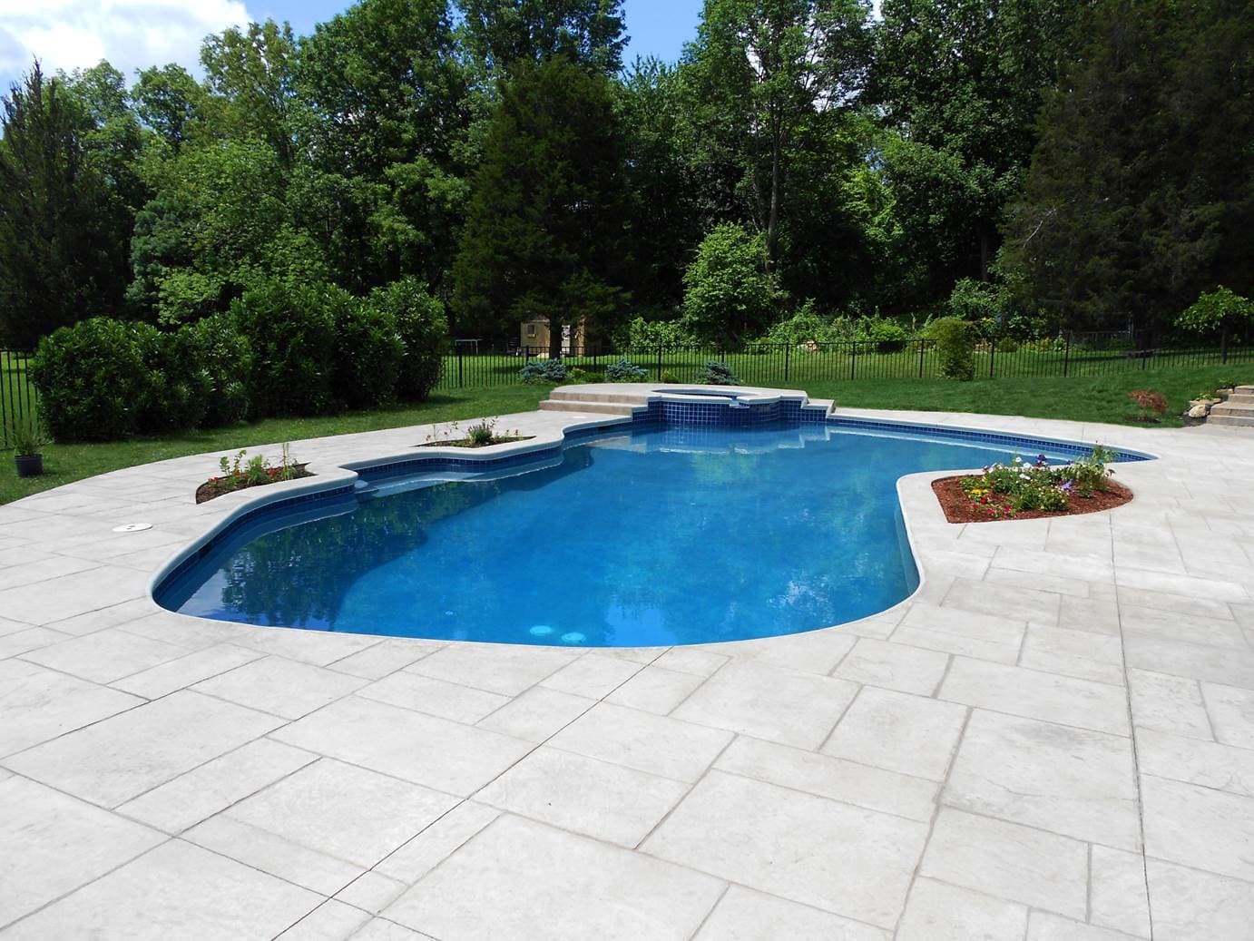 Award-winning freeform pool with attached spa, dam wall and marble-look deck pavers