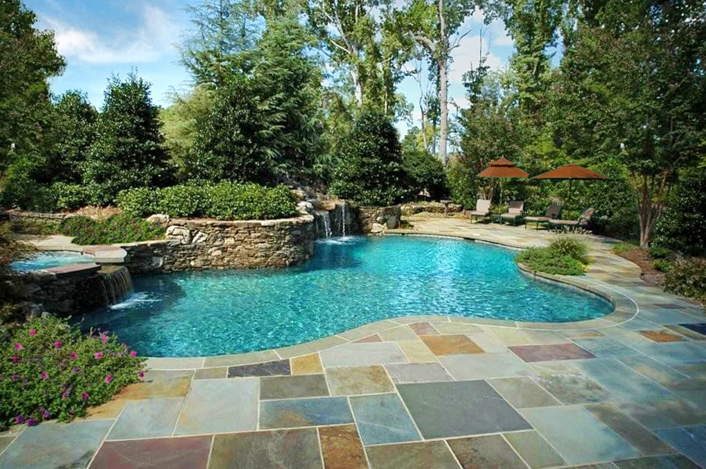 Freeform pool with raised stacked-stone spa, waterfall and multicolor flagstone deck — Premier Pool Renovations