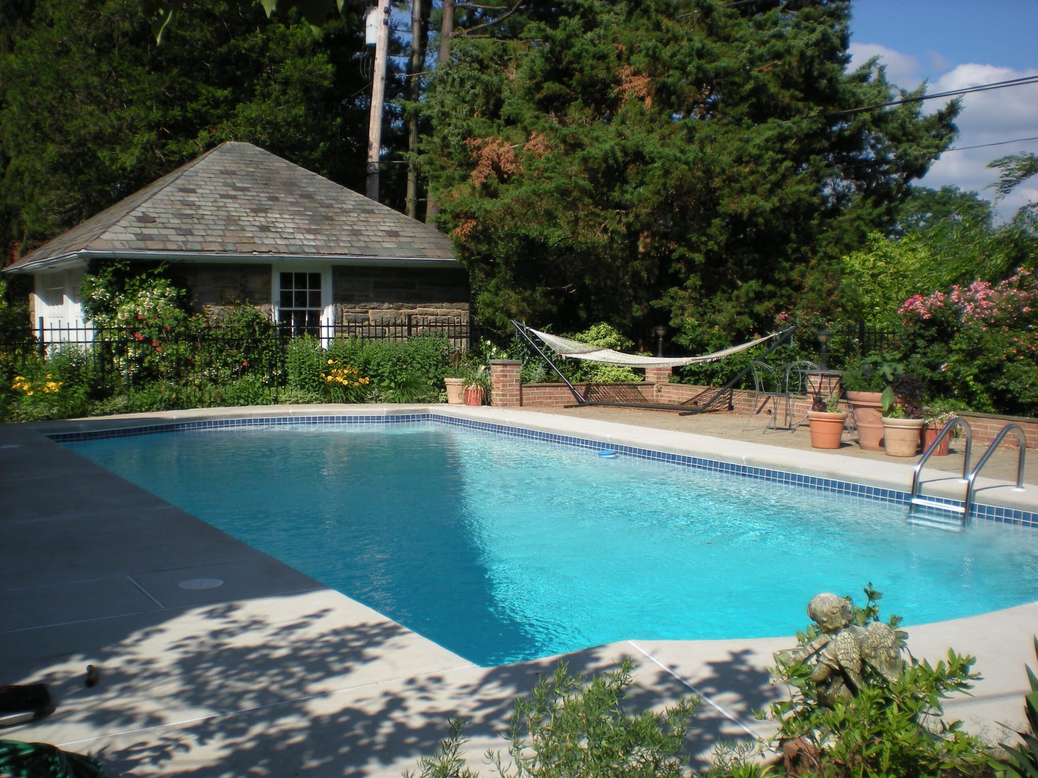 Rectangular pool with hammock and stone pool house with slate roof