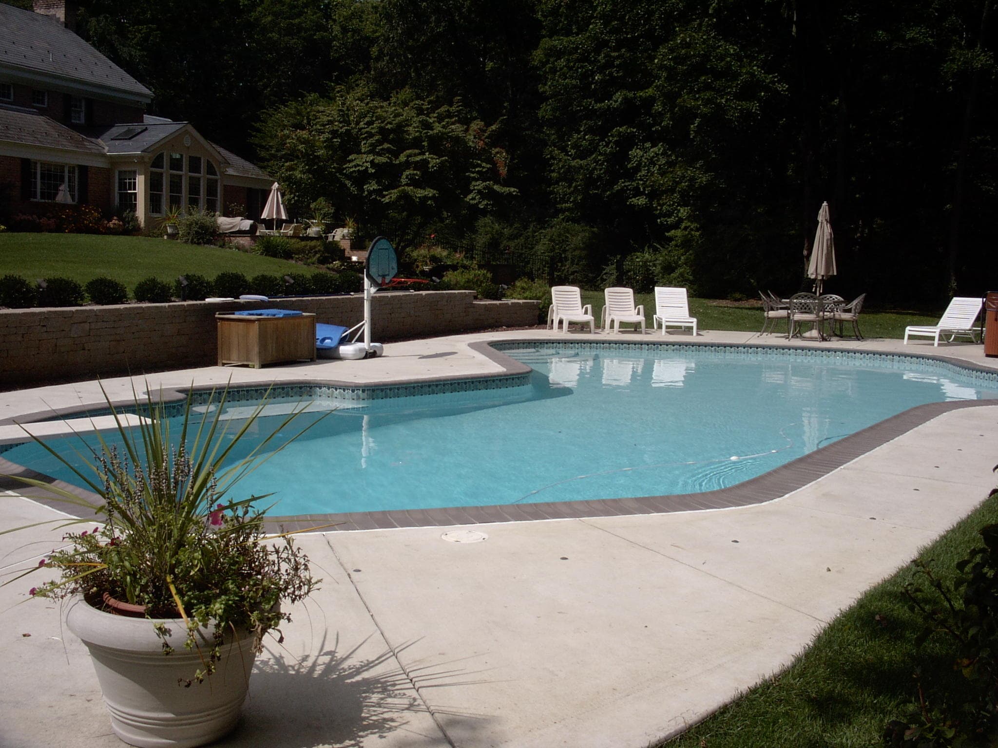 Rectangular pool with stacked-stone wall waterfall and attached spa on paver patio