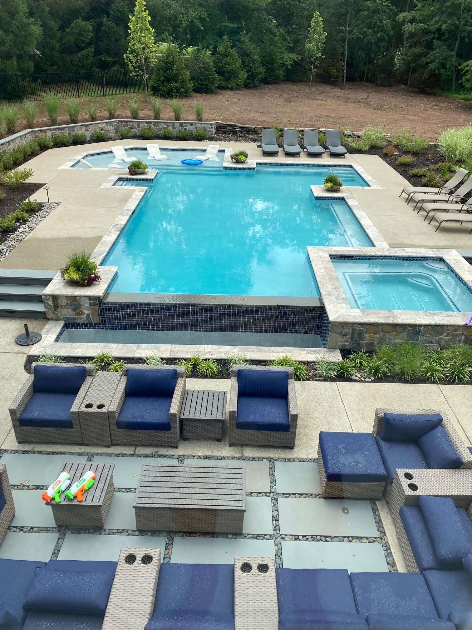 Pool and patio with blue sectional seating and cornhole game area