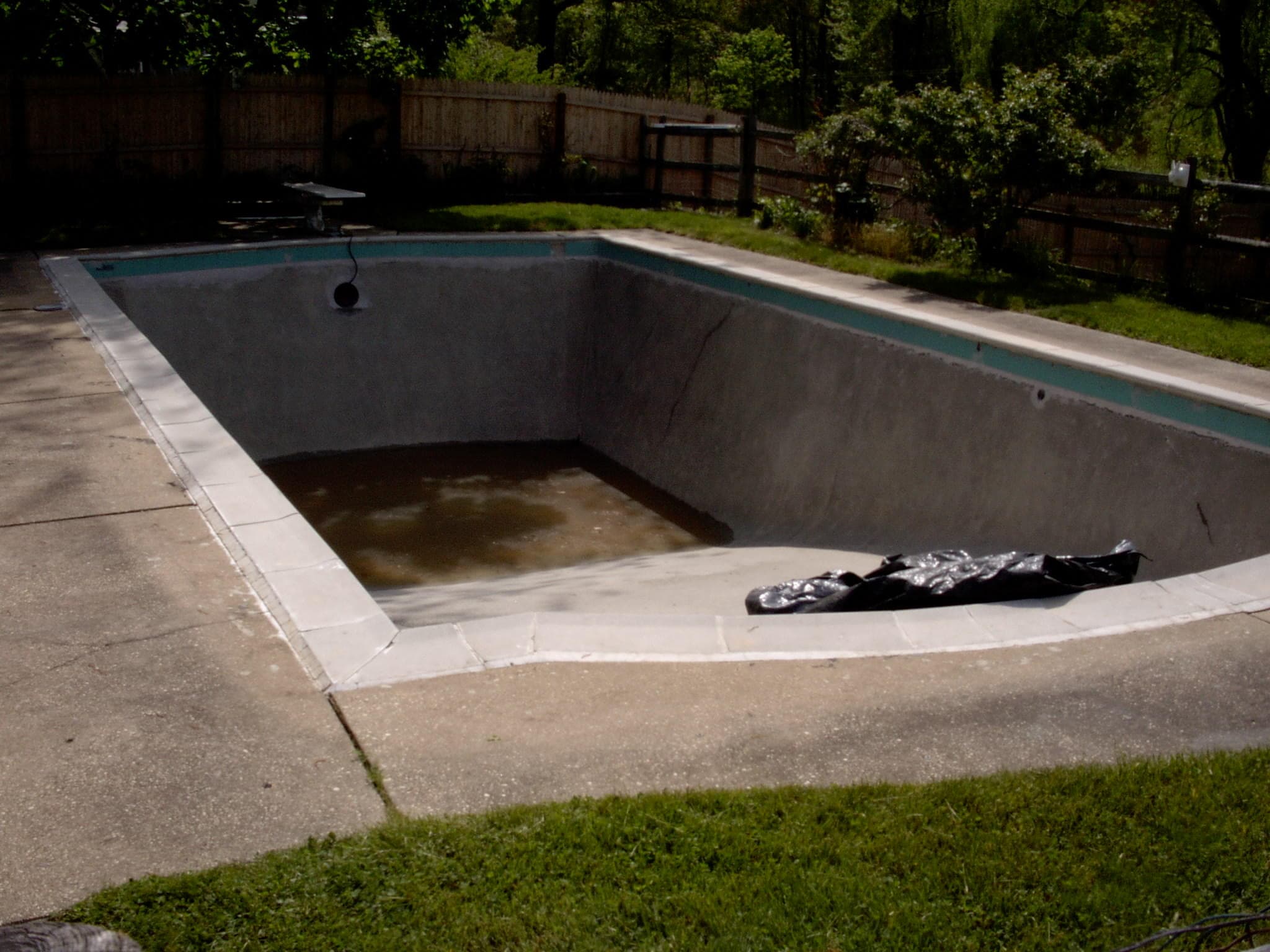 Kall pool before renovation: drained vinyl liner pool with stained walls and debris