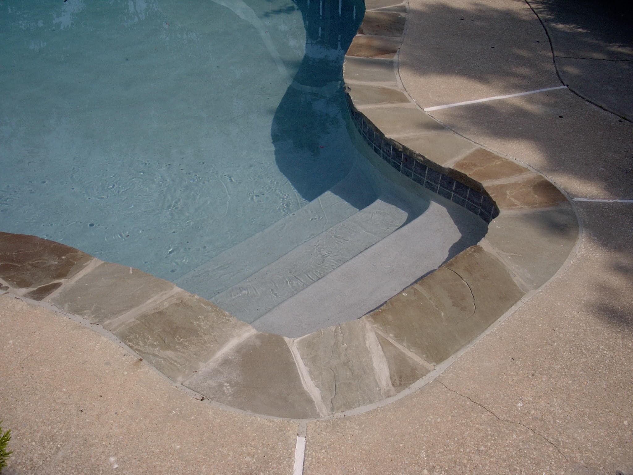 Light gray plaster finish on pool entry steps with irregular flagstone coping