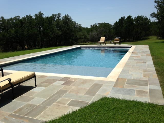 Rectangular pool with multicolor bluestone deck on open hill-country property