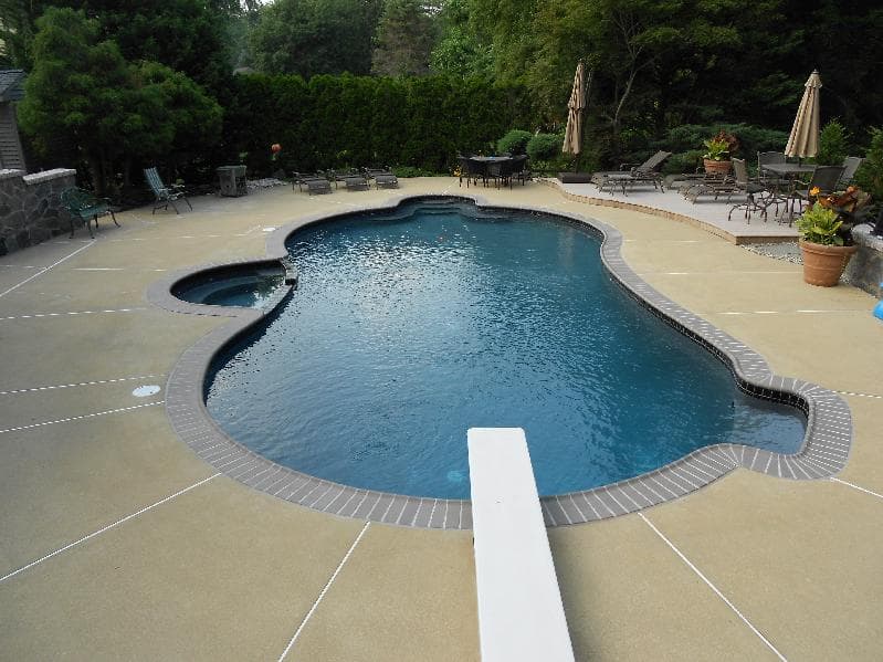 Freeform pool drained during renovation with crew demolishing surrounding deck