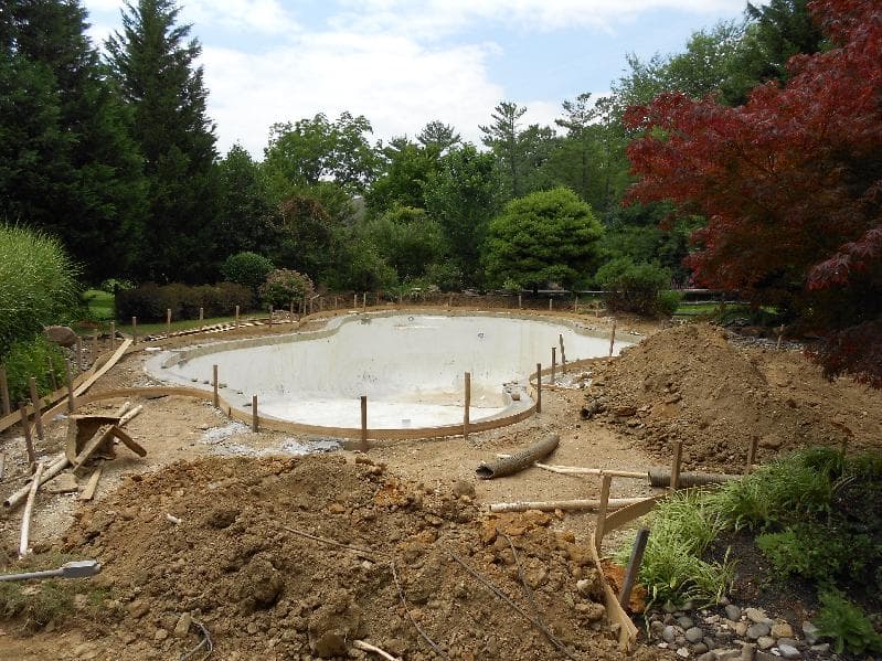 Freeform pool mid-demolition with concrete debris scattered around and workers on site