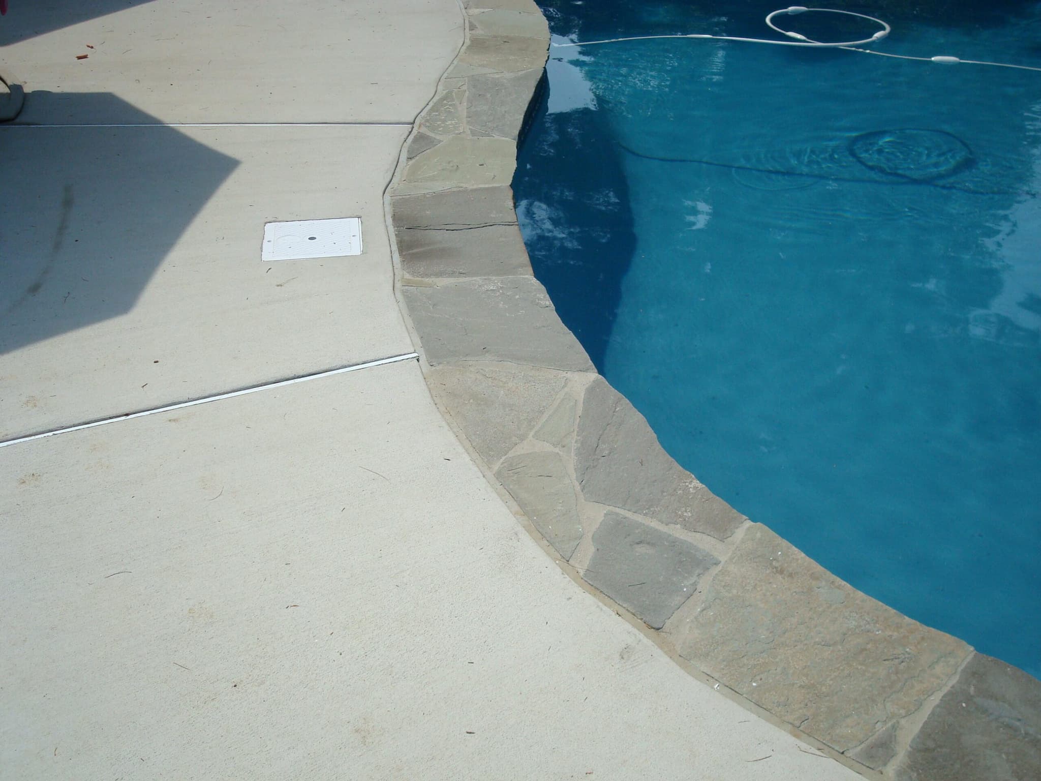 Detail of irregular flagstone pool coping transitioning to concrete deck
