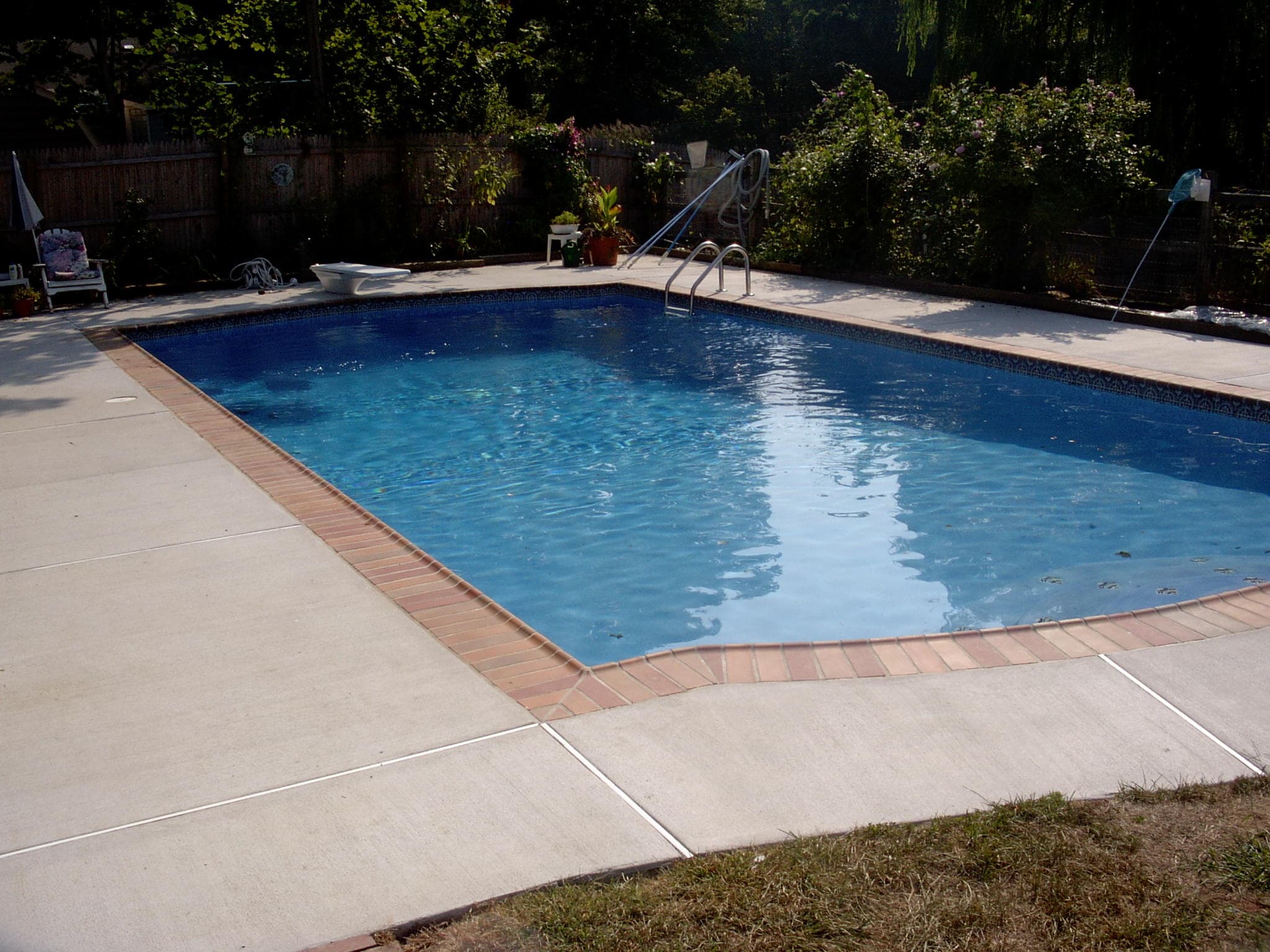 Lazy-L vinyl liner pool with brick coping and concrete deck after renovation
