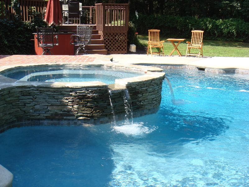 Premier crew constructing stacked-stone spa wall during pool renovation in Maryland backyard