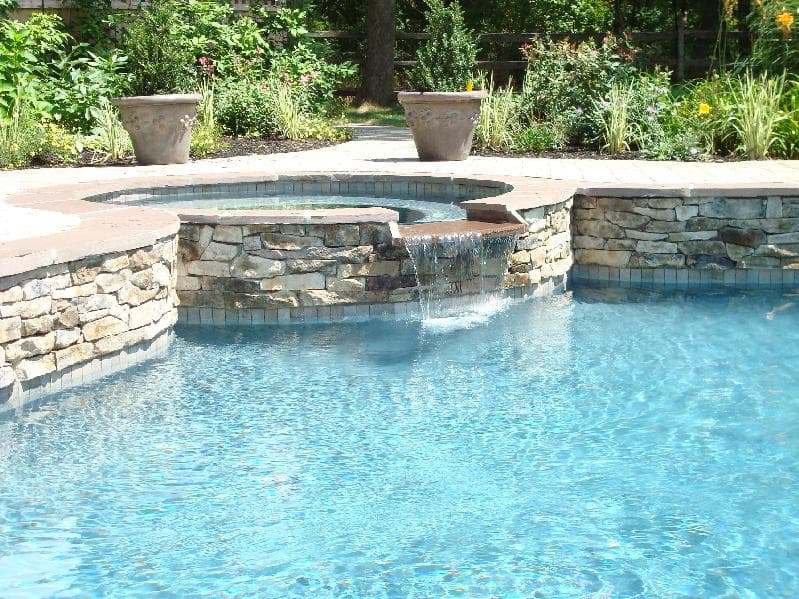 Stacked-stone spa with sheer-descent waterfall and lush garden surround