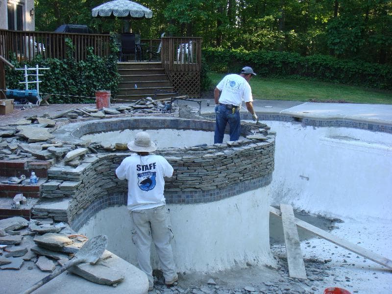 Premier crew constructing stacked-stone spa wall during pool renovation in Maryland backyard