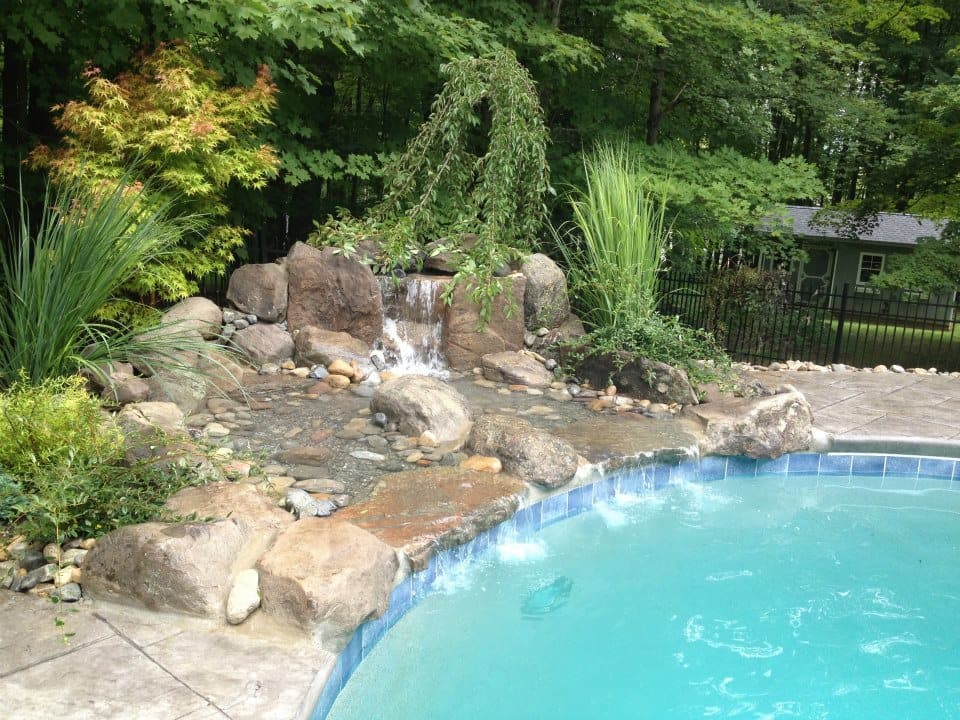 Naturalistic boulder waterfall with grasses and weeping cherry — Premier Pool Renovations