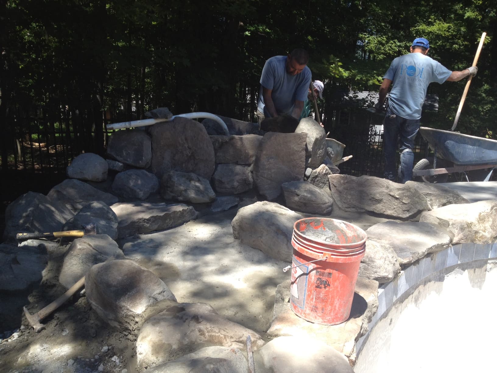 Building boulder waterfall during pool construction — Premier Pool Renovations