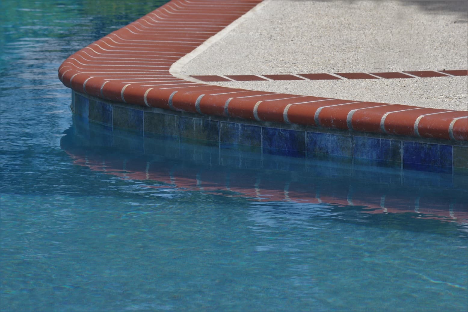 Plantation Red brick coping detail over blue waterline tile — Premier Pool Renovations